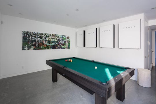 Custom-built rec room with 4 Tesla power panels installed on wall.