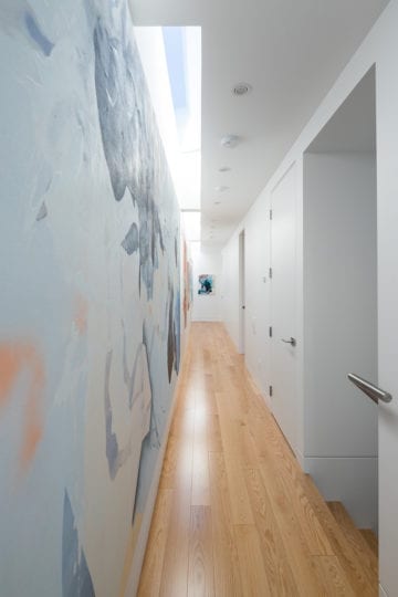 A custom built hallway featuring a skylight and wooden flooring in a North Vancouver home.