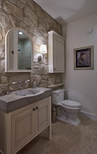 Ensuite bathroom in guest bedroom with stone wall and tile flooring.