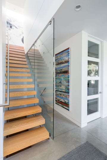 Modern wooden staircase with class wall in Barrett Group North Vancouver custom home.