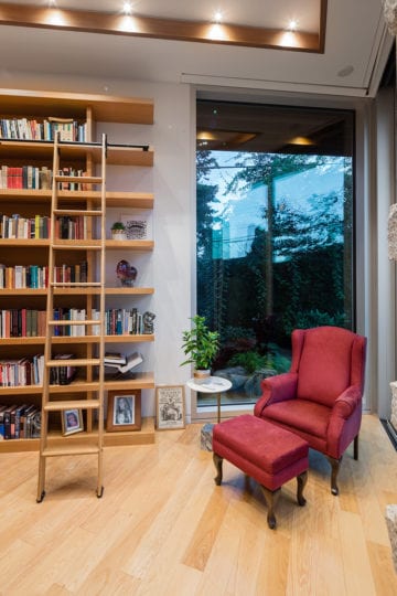 Indoor library seating area with sliding ladder in front of shelves in North Vancouver home.