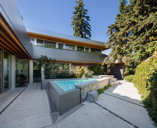 Custom-built outdoor space including a pool, stone tiles, and metallic siding.
