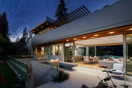 Outer patio of custom home with open sliding glass door. Features outdoor fireplace.