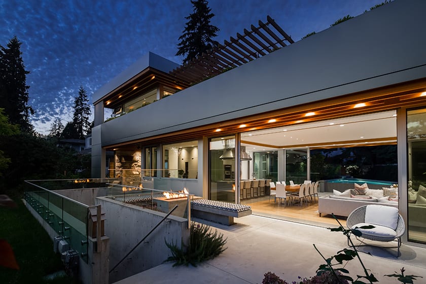 Outer patio of custom home with open sliding glass door. Features outdoor fireplace.