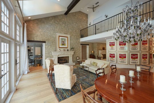 Upper floor balcony overlooking luxury living room. Features ceiling fans.