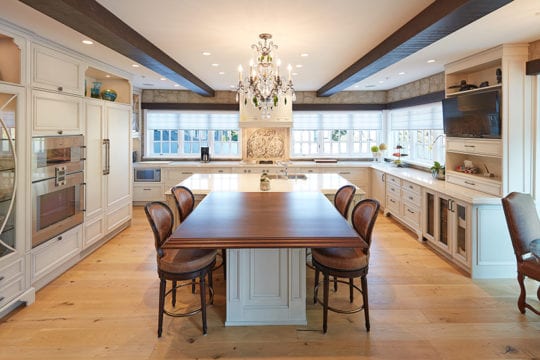 Luxury kitchen built by Barrett Group with hardwood flooring, chandelier, and an island counter.