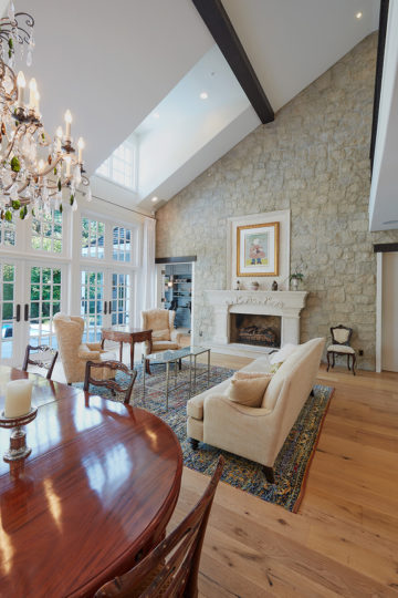 Stunning custom living space with fireplace on a stone wall and skylight and patio doors.