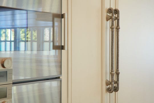 Shows beautiful metal handle of a wall oven in custom built kitchen by Barrett Group.